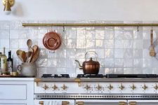 a beautiful vintage white kitchen with gold fixtures and a gorgeous white Zellige tile backsplash that adds shine, interest and texture