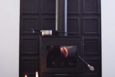 a black modern stove with a black panel wall behind it and a modern candelabra for a bold look