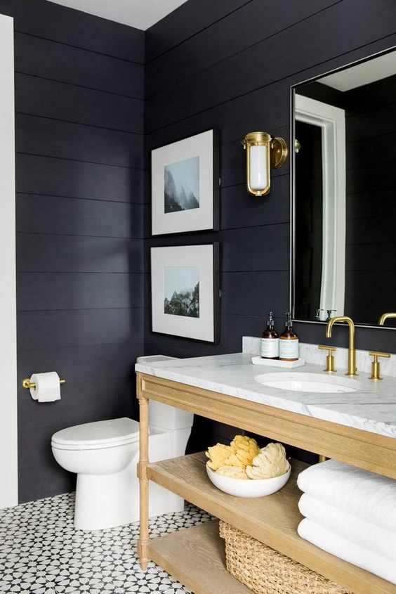 a chic and elegant bathroom with mosaic tiles, black shiplap walls, a light stained vanity and wall candle lanterns