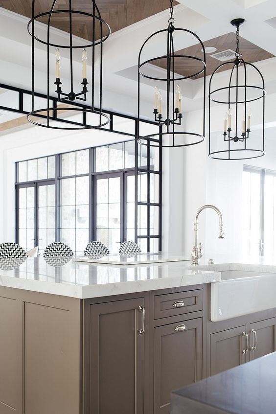 a chic taupe kitchen with shaker cabinets, white stone countertops and cage pendant lamps is a beautiful idea