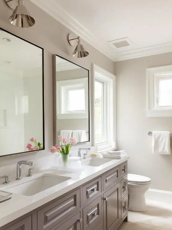 a chic vintage inspired bathroom in dove grey, with a taupe vintage double vanity, sconces and a white stone countertop