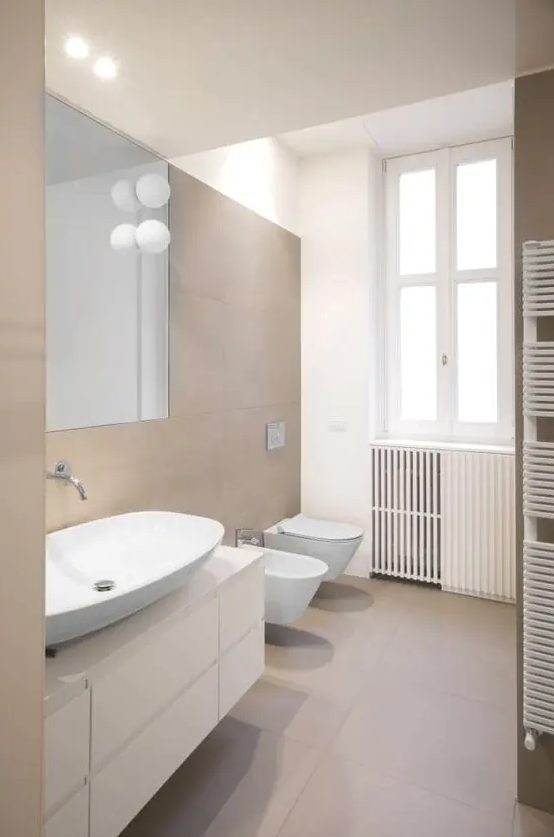 a contemporary bathroom clad with taupe tiles, a white floating vanity, white appliances and cool bubble lamps is cool