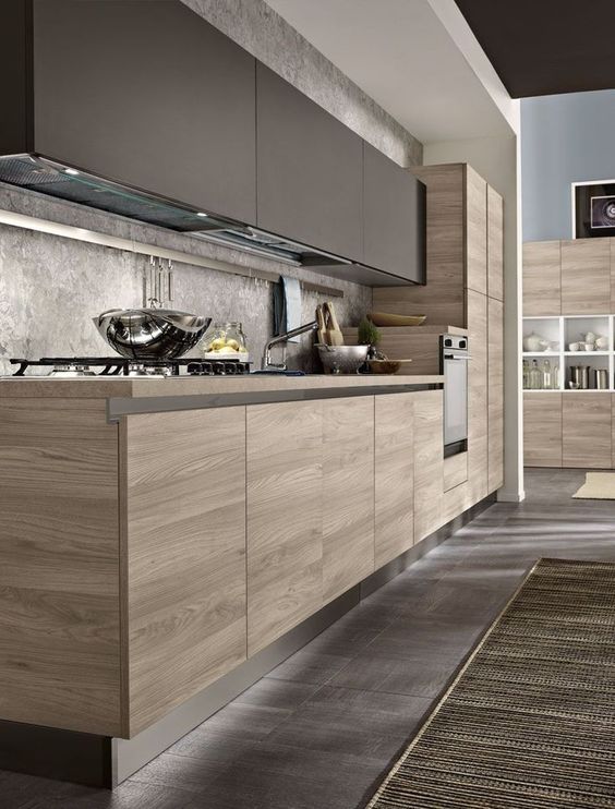 a contemporary kitchen with matte taupe cabinets, stained lower ones, a grey stone backsplash and countertops and metal touches