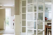a delicate white framed folding door is a perfect match for this neutral interior and it doesn’t look heavy at all