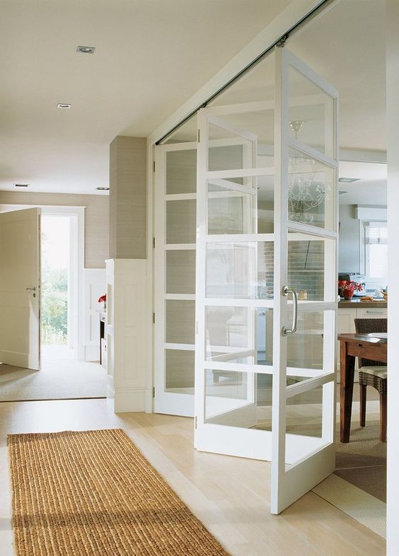 a delicate white framed folding door is a perfect match for this neutral interior and it doesn't look heavy at all