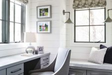a farmhouse home office done with white shiplap on the walls, comfy blue furniture, printed Roman shades and lamps on the walls