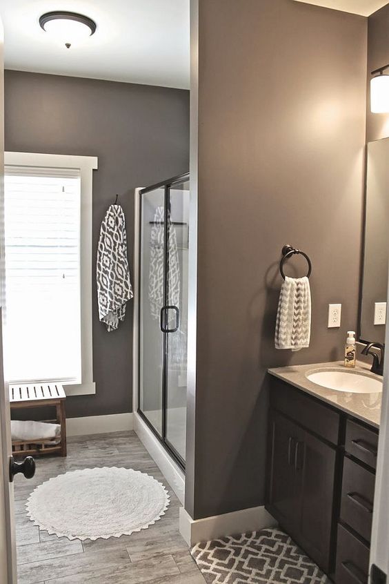 a farmhouse taupe bathroom, with a glass enclosed shower space, a black vanity and a window with blinds