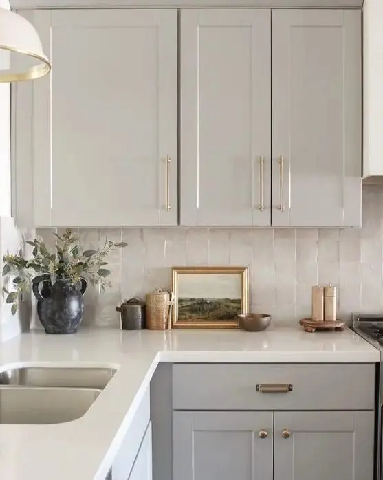 a grey kitchen with a neutral Zellige tile backsplash, a white stone countertop and pendant lamps is chic and lovely