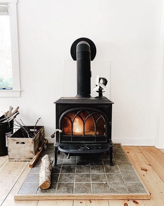 a large vintage black stove on a tile platform is a cool idea to add coziness to your home decor