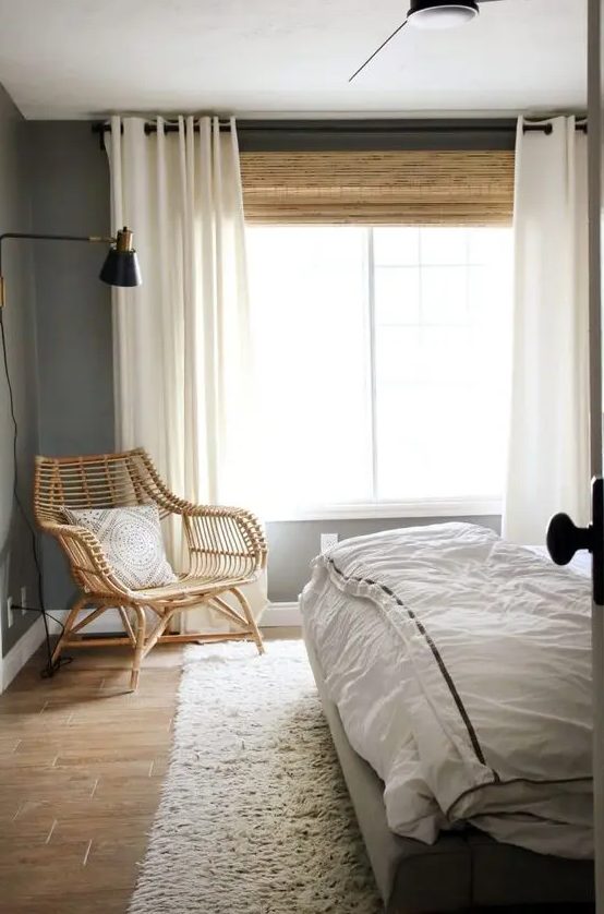 a large woven shade and creamy draperies add coziness and interest to the bedroom, and the shade echoes with the rattan chair