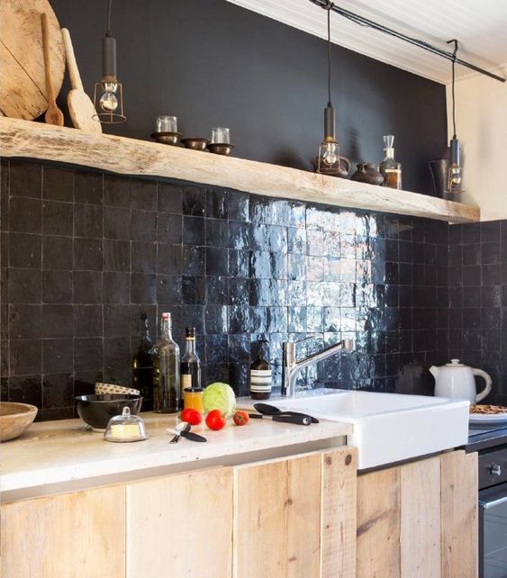 a light stained kitchen with a black Zellige tile backsplash, an open shelf and a white sink plus black bulbs hanging