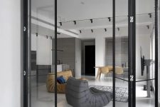 a minimalist home with black frame and glass folding doors that match the decor and make the spaces more airy and lightweight
