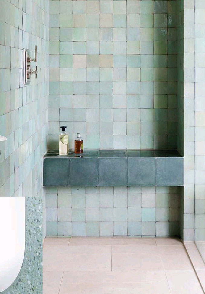 a modern bathroom fully clad with green Zellige tiles, with a black tiled shelf and neutral fixtures is chic