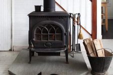 a modern farmhouse space with a vintage black wood burning stove and a cozy rug next to it