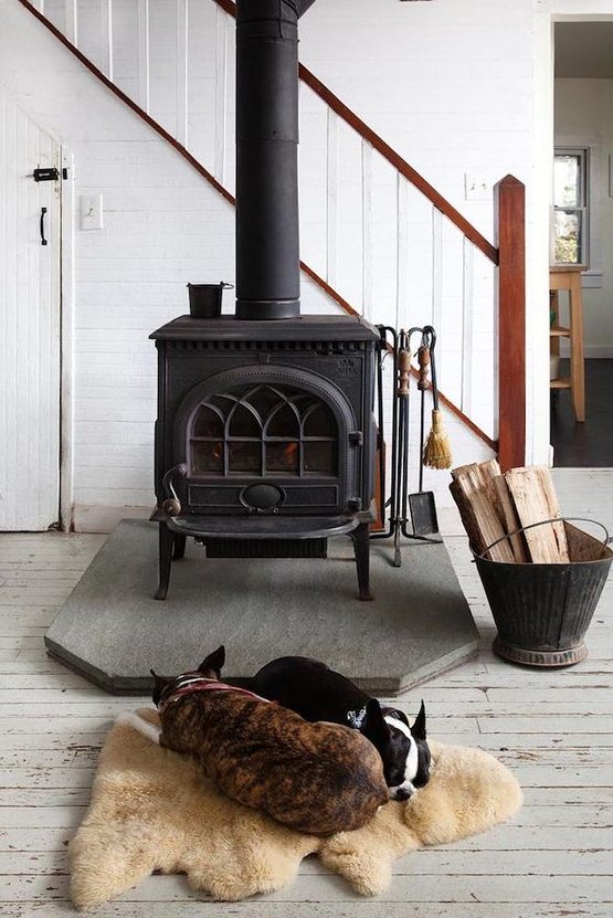a modern farmhouse space with a vintage black wood burning stove and a cozy rug next to it