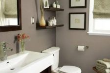a modern taupe bathroom with a dark stained vanity, a wooden stool and shelves, white appliances, green touches and a mini gallery wall