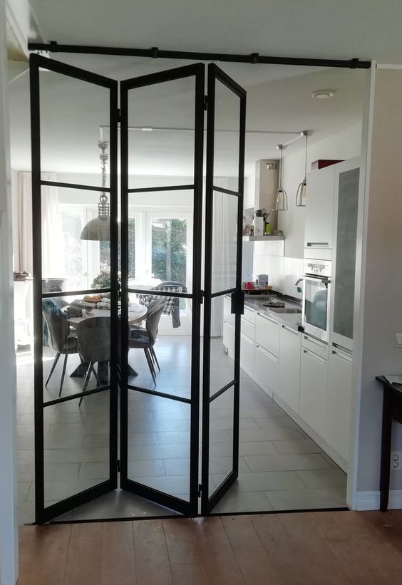 a modern white kitchen with a black frame glass folding door is a cool idea for a contemporary or modern space
