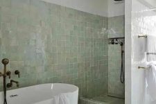 a neutral bathroom with bathing spaces clad with green Zellige tiles and the rest of the space done with usual white ones
