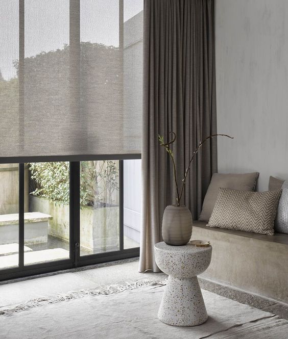 a neutral contemporary space featuring various shades of neutrals, semi-sheer shades for a privacy and grey curtains for light blocking