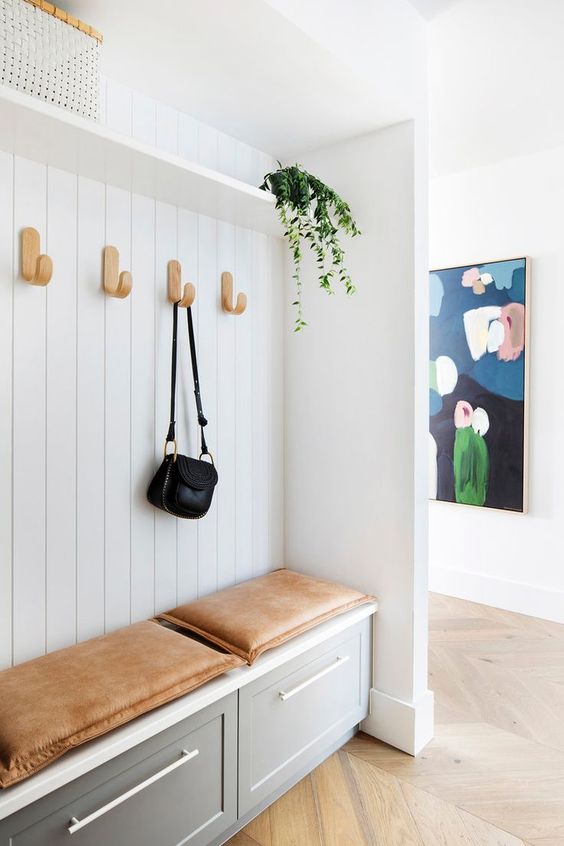 a neutral entryway with shiplap and grey storage cabinets, plywood hooks and potted greenery, leather cushions