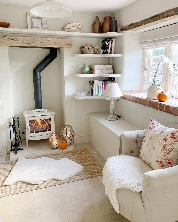 a neutral living room with a white hearth, open shelving, a neutral chair, layered rugs and a storage cabinet