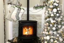 a pretty Christmas styled nook with a hearth, stockings, greenery, a white wreath and a gorgeous silver Christmas tree with lights