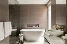 a refined bathroom with taupe and white marble tiles, a large shower space and an oval tub, a dark stained vanity and a large window for natural light