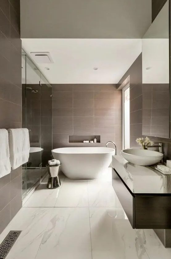 a refined bathroom with taupe and white marble tiles, a large shower space and an oval tub, a dark stained vanity and a large window for natural light
