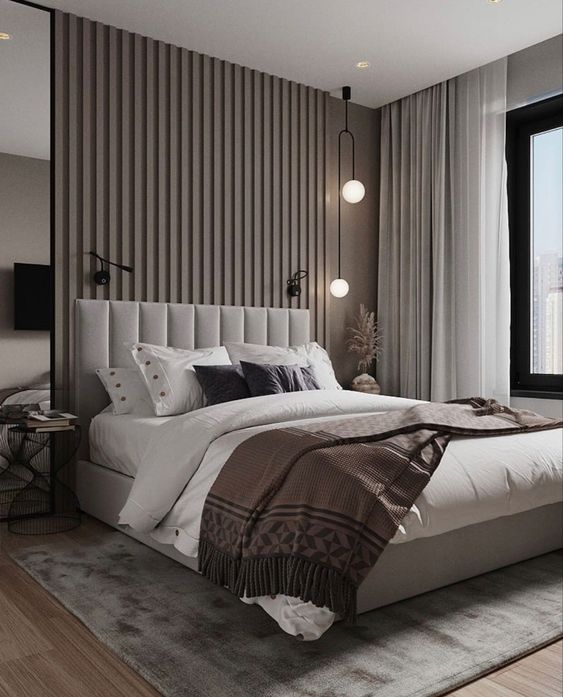 a refined contemporary bedroom with a taupe accent wall done with wood slabs, a grey upholstered bed, a pendant lamp and sconces