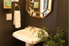 a small vintage powder room with taupe walls, a free-standing sink, a small side table and a tiny gallery wall feels elegant