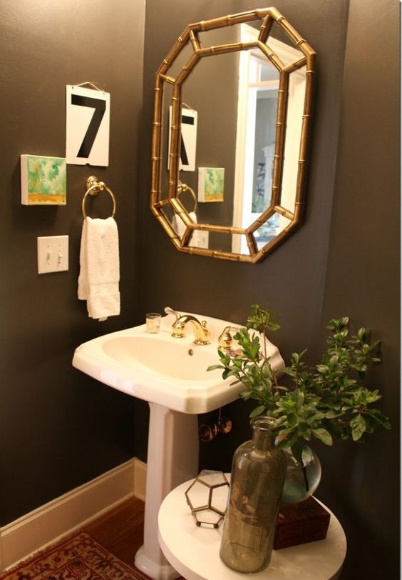 a small vintage powder room with taupe walls, a free standing sink, a small side table and a tiny gallery wall feels elegant