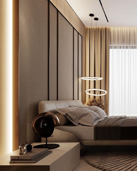 a sophisticated warm-colored bedroom with a taupe accent wall, a tan leather bed and brown and grey bedding, circle pendant lamps