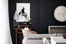 a stylish contemporary living room highlighted with black shiplap on the wall, neutral furniture accents it even more