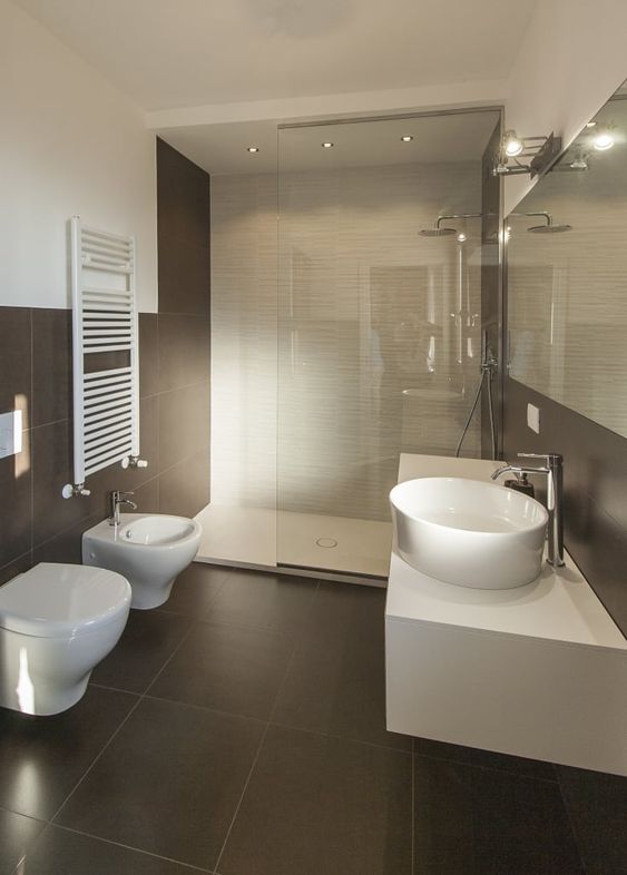 a stylish modern bathroom clad with neutral and taupe tiles, with a white floating vanity and white appliances