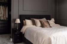 a stylish taupe bedroom with a closet, a black bed with neutral bedding, blakc nightstands and a fluffy pendant lamp