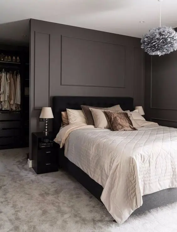 a stylish taupe bedroom with a closet, a black bed with neutral bedding, blakc nightstands and a fluffy pendant lamp