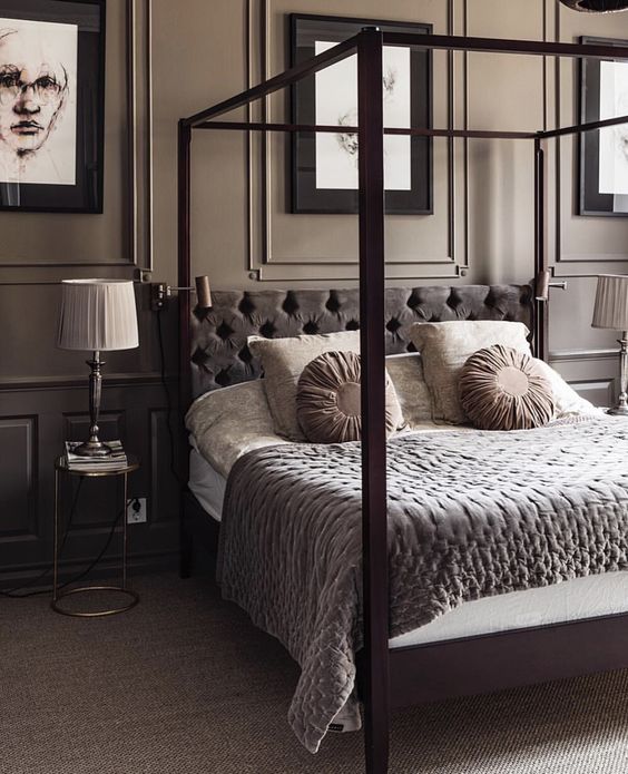 a tan bedroom with panels, a taupe canopy bed, taupe and beige bedding, a gallery wall and chic nightstands