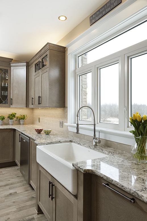 a traditional vintage kitchen with a white stone countertop, a tan tile backsplash, built-in lights and a window for a view