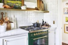 a vintage kitchen with white shaker style cabinets, white stone countertops, an open shelf, some art and a white Zellige tile backsplash