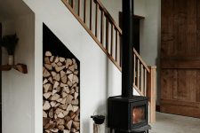 a welcoming and natural entryway with a wood burning stove, firewood stored under the stairs and layered rugs is very cozy