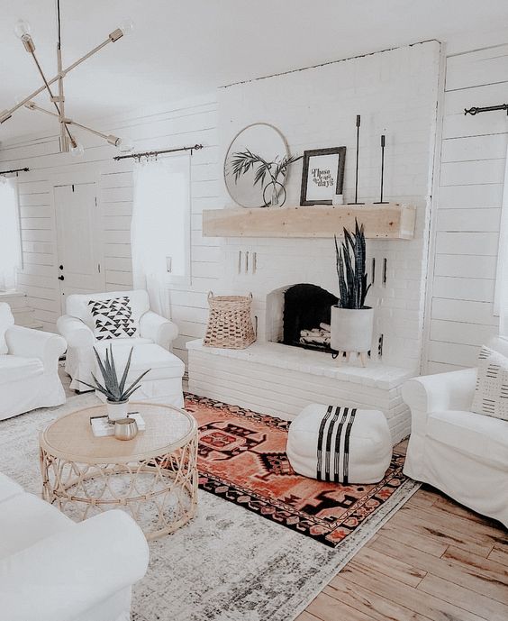 a welcoming white boho living room with white shiplap walls, a white brick fireplace and touches of rattan
