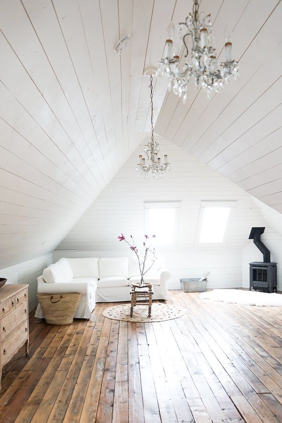 a white attic living room all done with white shiplap around and stained shiplap on the floor looks very cozy and airy