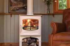 a white wood burning stove is an elegant idea, firewood under it is a cool idea to store it