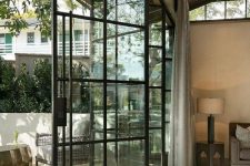 an airy black frame glass bi-fold door is a cool solution to separate the inside space and the outdoor one connecting them in a tight way