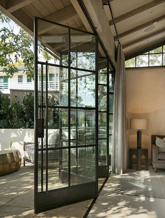 an airy black frame glass bi-fold door is a cool solution to separate the inside space and the outdoor one connecting them in a tight way