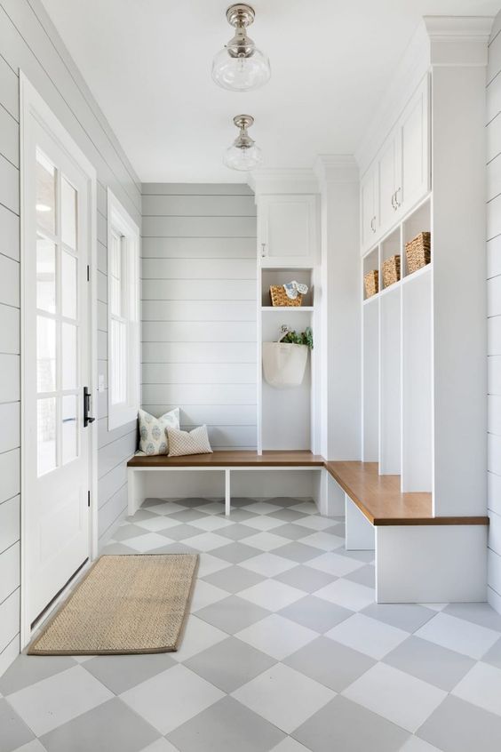 an airy mudroom with dove grey shiplap walls, a large storage unit with cabinets and open shelving, elegant glass lamps