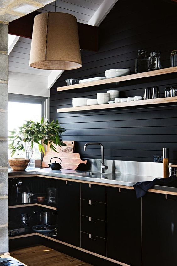 an elegant black kitchen done with black shiplap on the wall for a statement and texture and sleek black plywood cabinets with touches of neutral stain