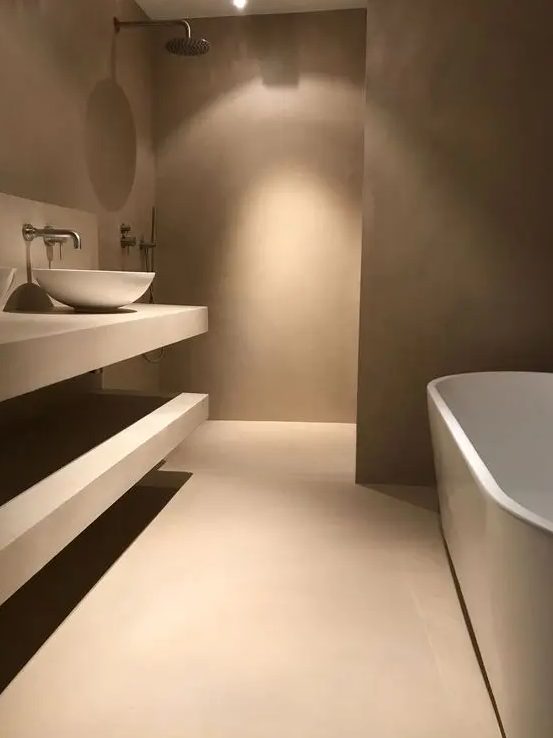 an ultra minimalist taupe bathroom with matte walls and a floor, open shelves, an oval taupe tub and a white bowl sink is amazing
