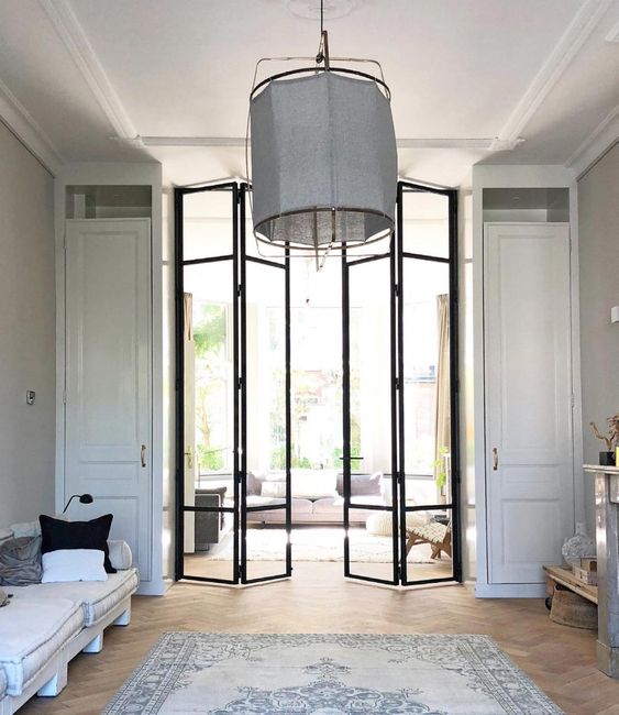 double height black frame bi fold doors let more light in the space and almost create one single space of two rooms
