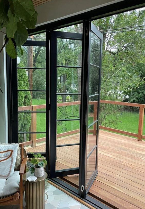 pretty black frame bi-fold doors leading a terrace with a wooden deck is a lovely idea to stay closer to outdoors